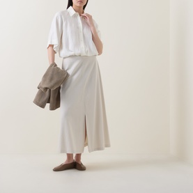 Model wearing Marc O Polo Textured Drawstring Blouse in white with a cream midi skirt, styled with taupe mules and carrying a khaki jacket.