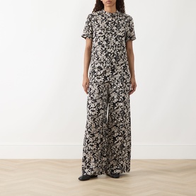Model wearing Marc O Polo Floral Fluid Blouse in black multi with matching wide-leg floral trousers and black flat shoes.