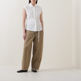 Model wearing Marc O Polo Textured Waist-Tie Blouse in white, sleeveless with waist tie, styled with wide-leg tan trousers and black flats.