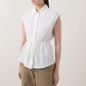 Model wearing Marc O Polo Textured Waist-Tie Blouse in white, sleeveless with kent collar, concealed placket and waist tie, styled with khaki trousers