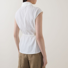 Model wearing Marc O Polo Textured Waist-Tie Blouse in white, showing back view with waist tie, crinkle texture, and sleeveless design. Styled with
