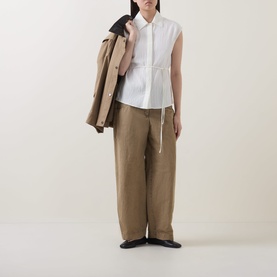 Model wearing Marc O Polo Textured Waist-Tie Blouse in white, sleeveless with waist tie, styled with khaki wide-leg trousers and dark jacket draped