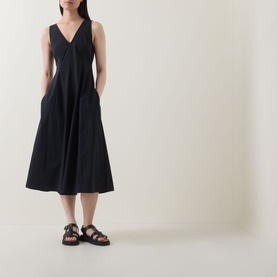 Model wearing Marc O Polo Woven Flared Dress in black, sleeveless V-neck midi length with flared skirt, styled with black chunky sandals