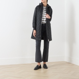 Model wearing Marc O Polo black quilted longline coat with hood, styled with striped top, dark cropped jeans and black loafers.