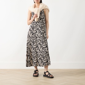 Model wearing Marc O Polo black multi floral midi dress, styled with cream knit scarf and black chunky sandals.