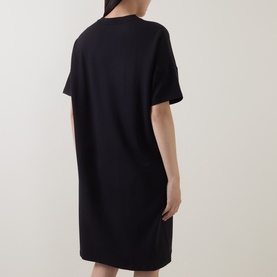Model wearing Marc O Polo Solid Sweatshirt Dress in black, short sleeves, dropped shoulders, straight mini-length silhouette, rear view
