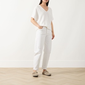 Model wearing Marc O Polo White Cotton knit V-neck top with short sleeves, styled with white straight-leg jeans and beige mules.