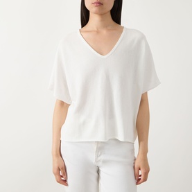 Model wearing Marc O Polo White Cotton knit top with V-neck and short sleeves, styled with white trousers.