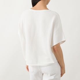 Model wearing Marc O Polo White Cotton knit top, short sleeves, relaxed boxy fit, styled with white trousers, rear view.