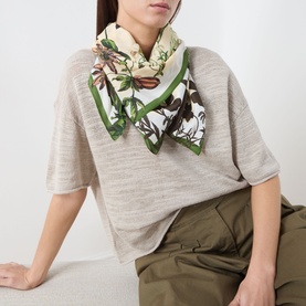 Model with Marc O Polo Floral Print Scarf in light beige multi, square silk-style scarf with green border and floral print, tied at neck