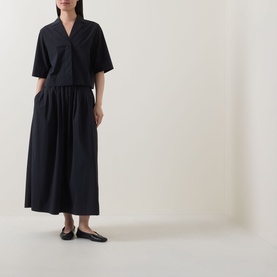 Model wearing Marc O Polo black gathered midi skirt with elasticated waist, styled with matching black short-sleeve top and black ballet flats.