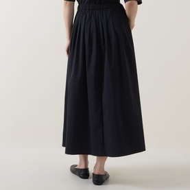 Model wearing Marc O Polo black gathered midi skirt in cotton blend, styled with black flat shoes, rear view.