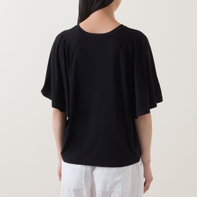 Model wearing Marc O Polo black T-shirt, back view, with flutter sleeves and relaxed fit, styled with white wide-leg trousers
