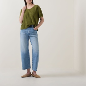 Model wearing Marc O Polo Wide Slub T-Shirt in Shaded Fern with wide V-neck and dropped shoulders, styled with light blue wide-leg jeans and tan