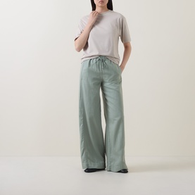 Model wearing Marc O Polo Solid Relaxed T-Shirt in Linen Beige with round neck and short sleeves, styled with sage green wide-leg trousers.