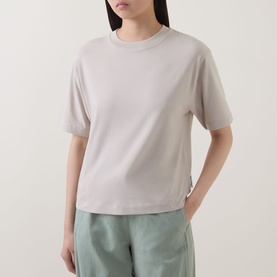 Model wearing Marc O Polo Solid Relaxed T-Shirt in Linen Beige, round neckline, dropped shoulders, short sleeves, styled with sage green trousers.