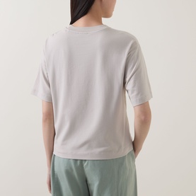 Model wearing Marc O Polo Solid Relaxed T-Shirt in Linen Beige, back view, short sleeves, dropped shoulders, styled with sage green trousers.