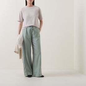 Model wearing Marc O Polo Solid Relaxed T-Shirt in Linen Beige with sage wide-leg trousers, holding a cream knit cardigan.