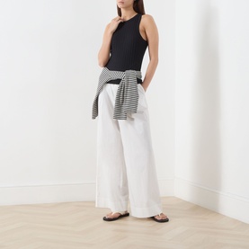 Model wearing Marc O Polo black modal-cotton T-shirt with white wide-leg trousers and striped shirt tied at waist.