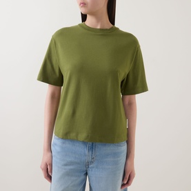 Model wearing Marc O Polo Solid Relaxed T-Shirt in Shaded Fern, short sleeves, dropped shoulders, styled with light blue jeans.