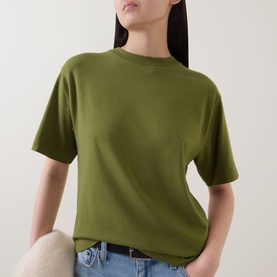 Model wearing Marc O Polo Solid Relaxed T-Shirt in Shaded Fern, round neckline, dropped shoulders, styled with blue jeans
