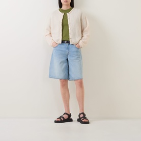 Model wearing Marc O Polo Solid Relaxed T-Shirt in Shaded Fern, styled with a cream cardigan, light blue denim shorts, and black sandals.