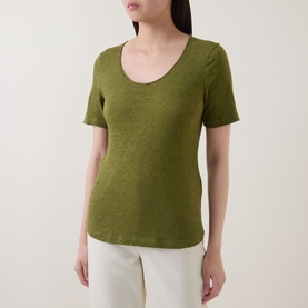 Model wearing Marc O Polo Solid Slub T-Shirt in Shaded Fern, scoop neckline, short sleeves, slub jersey finish, styled with white trousers