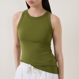 Model wearing Marc O Polo Solid Logo Tank Top in Shaded Fern, round neck, wide straps, styled with white drawstring trousers.
