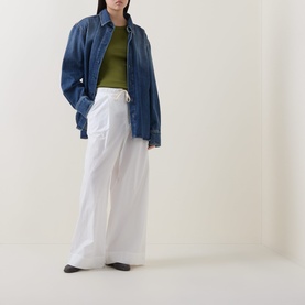 Model wearing Marc O Polo Solid Logo Tank Top in Shaded Fern, styled with oversized blue denim shirt and wide-leg white trousers.