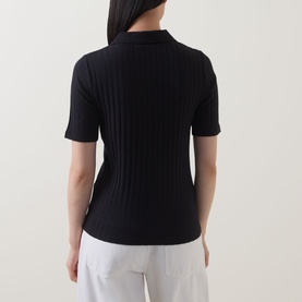 Model wearing Marc O Polo Pointelle Polo Sweater in black, ribbed short-sleeve knit, back view, styled with white trousers