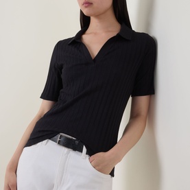 Model wearing Marc O Polo Pointelle Polo Sweater in black, ribbed knit with polo collar and V-neckline, styled with white jeans and black belt.