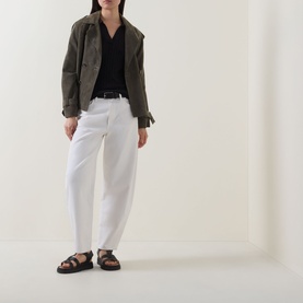 Model wearing Marc O Polo Pointelle Polo Sweater in black with white trousers, olive utility jacket, and black sandals