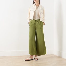 Model wearing Marc O Polo Shaded Fern wide-leg trousers with drawstring waist, styled with cream denim jacket and slide sandals.