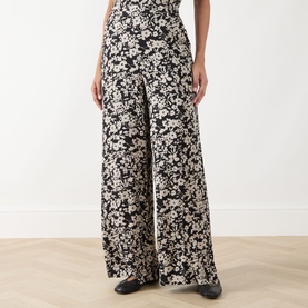 Model wearing Marc O Polo Floral Wide Leg Trousers in black multi, wide-leg silhouette with elasticated waist and allover floral print.