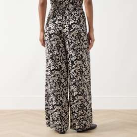 Model wearing Marc O Polo Floral Wide Leg Trousers in black multi, wide-leg silhouette with all-over floral print and elasticated waistband.