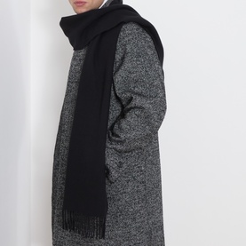 Model with Eton Solid Fringe Scarf in black, draped over shoulders, styled with a grey marl overcoat. Fringed ends visible.