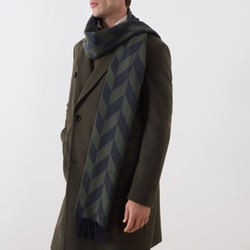 Model with Eton Logo Chevron Fringe Scarf in dark green, draped over olive wool overcoat, featuring bold chevron pattern and fringed ends.