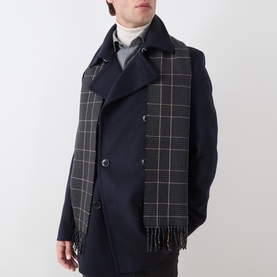 Model with Eton Prince of Wales Check Scarf in black wool, fringed ends, styled over navy double-breasted coat with roll-neck