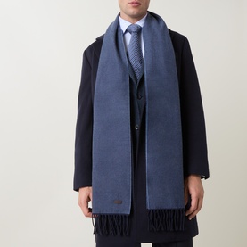 Model with Eton Logo Twill Fringe Scarf in blue, draped over navy coat and suit, featuring fringed ends and logo plaque