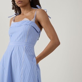 Model wearing Jonathan Simkhai Avaleigh Stripe Dress in Oxford Blue Stripe, featuring lace-trimmed square neckline, bustier bodice and self-tie straps
