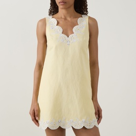 Model wearing Jonathan Simkhai Edena Embroidered Linen Mini Dress in Buttercream with white scalloped trim and broderie detailing