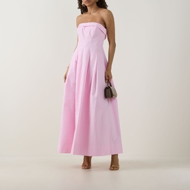 Model wearing Jonathan Simkhai Avril Bustier Dress in Daisy pink, strapless maxi with pleated skirt, styled with strappy heels and mini bag