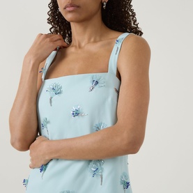 Model wearing Jonathan Simkhai Ella Embellished Mini Dress in blue with square neckline, fixed straps and floral embellishments