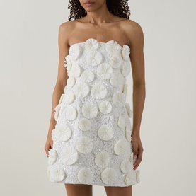 Model wearing Jonathan Simkhai Holland Floral Raffia Bustier Mini Dress in white with 3D floral raffia embellishments and straight strapless neckline.