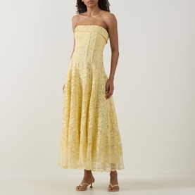 Model wearing Jonathan Simkhai Imogen Lace Bustier Dress in buttercream, strapless midi with floral lace and pleated skirt, styled with strappy heels