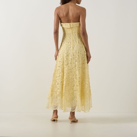 Model wearing Jonathan Simkhai Imogen Lace Bustier Dress in buttercream, strapless midi with floral lace and pleated skirt, back view, styled with