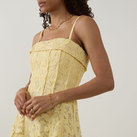 Model wearing Jonathan Simkhai Imogen Lace Bustier Dress in Buttercream, floral lace bodice with thin straps, styled with gold chain necklace and