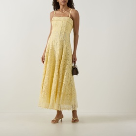 Model wearing Jonathan Simkhai Imogen Lace Bustier Dress in buttercream, midi-length floral lace with pleated skirt, styled with strappy sandals and
