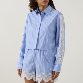Model wearing Jonathan Simkhai Renata Cropped Embellished Shirt in Oxford Blue Stripe with lace sleeve detail, styled with matching lace-trim shorts.