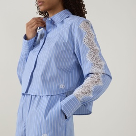 Model wearing Jonathan Simkhai Renata Cropped Embellished Shirt in Oxford Blue Stripe with lace sleeve detail, styled with matching wide-leg trousers.